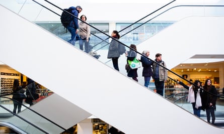 Shoppers ride up an escalator in the John Lewis flagship store on Oxford Street in London.