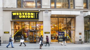 An image of people walking in front of a Western Union storefront