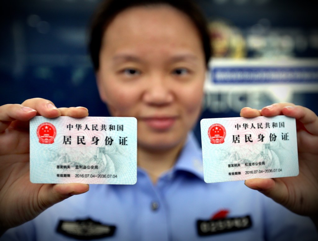 A police officer shows two identification cards to be issued to nonlocal residents at Zhoujiaqiao police station in east China's Shanghai Municipality