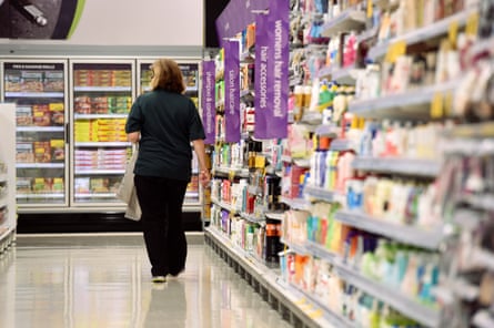 A stock image of a woman walking through a product isle in a Woolworths supermarket.