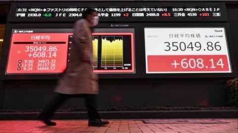 Man walks in front of Tokyo Stock Exchange signboards