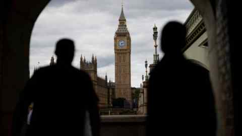 Two people walk under an arch in London with Big Ben in the distance