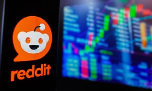The Reddit logo is displayed on a smartphone screen, with a graphic representation of the stock market in the background